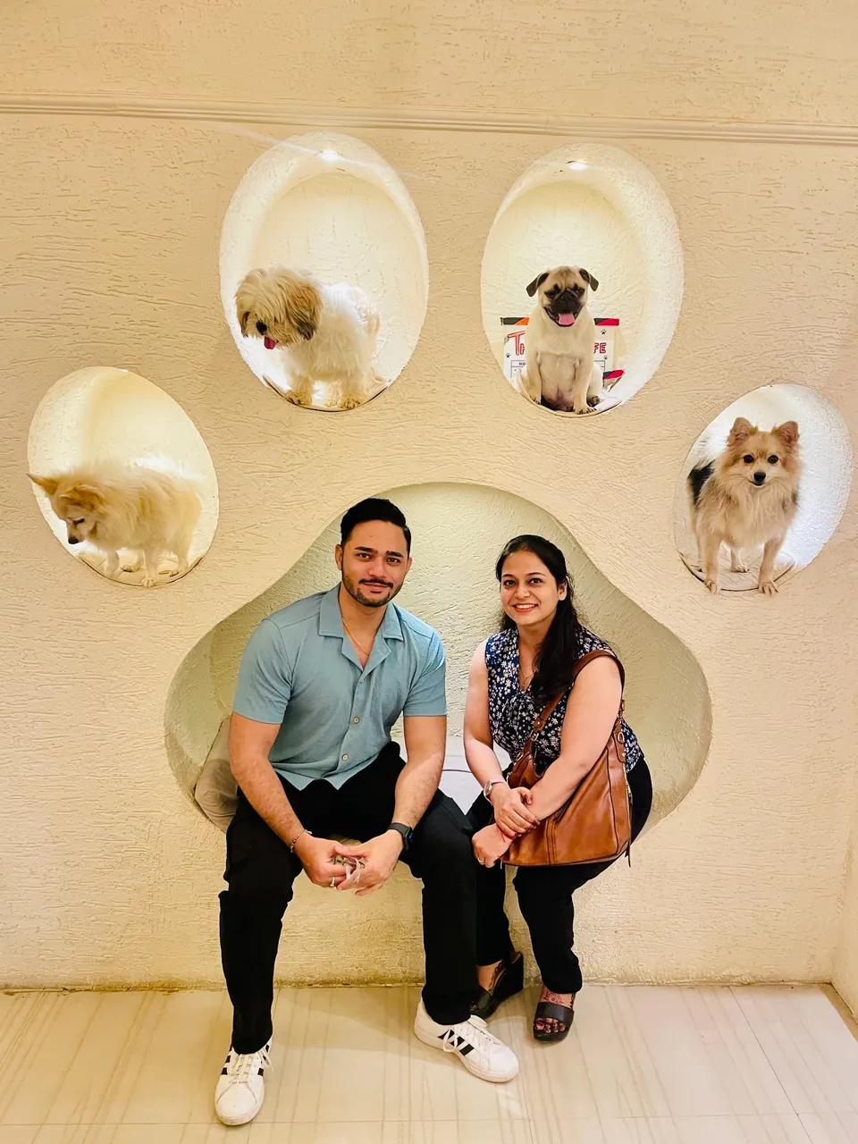 Rahul and a companion sitting at a café beneath a paw-shaped display with four dogs